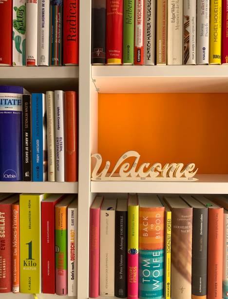 multi colored books in shelves and a welcome sign in empty part - library book shelf generic imagens e fotografias de stock