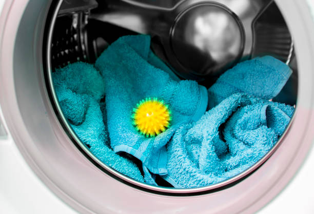 Using pvc dryer balls is natural alternative to both dryer sheets and liquid fabric softener, balls help prevent laundry from clumping in the dryer. Yellow spiky dryer ball between blue soft towels. Using pvc dryer balls is natural alternative to both dryer sheets and liquid fabric softener, balls help prevent laundry from clumping in the dryer. Yellow spiky ball between blue soft bath towels. tumble dryer stock pictures, royalty-free photos & images