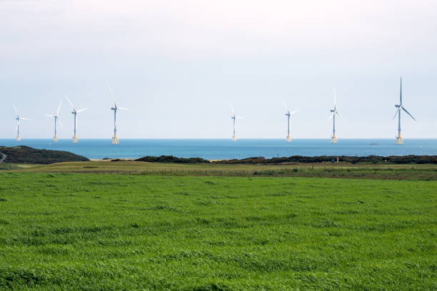 Offshore wind turbine off the coast of Scotland on a cloudy morning View of an offshore wind farm along the coast of Scotland with a cultivated field and a golg course in foreground aberdeen scotland photos stock pictures, royalty-free photos & images