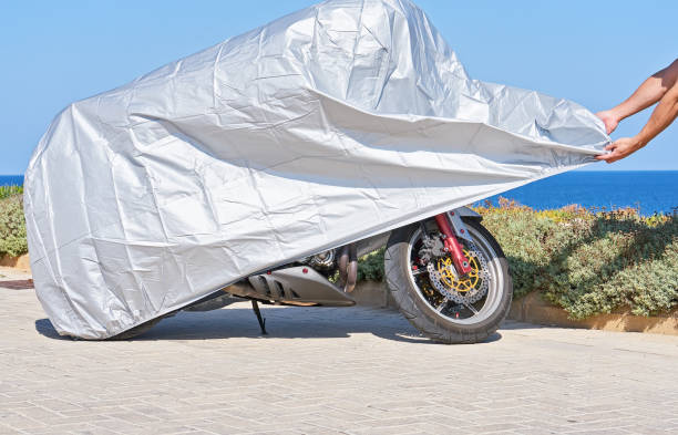 istock Biker covers motorcycle with waterproof cover with silver reflective surface 1183401712