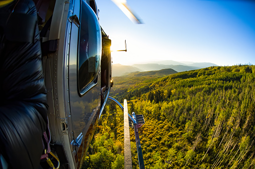 Flying in a Helicopter with Doors Off - Scenic views flying high above mountains and fall autumn foliage.