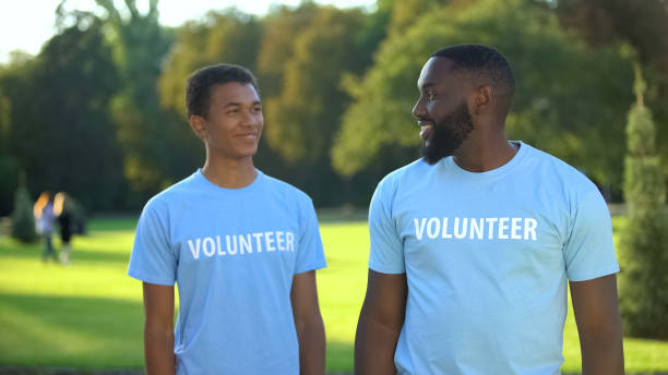 istock Glad male volunteers smiling to each other, eco project participation, help 1183419532