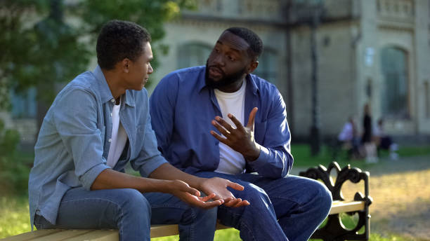 istock Father arguing teenage son sitting on campus bench, puberty age difficulties 1183419540