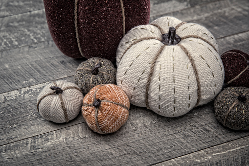 This is a close up photo of a group of quilted cloth pumpkins on a wood table background. There is space for copy. This is a nice  image that would work well for autumn, Thanksgiving and a holiday season in the fall.