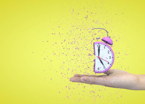 istock Alarm clock pink on a yellow background explodes in the girl's hands 1183423038