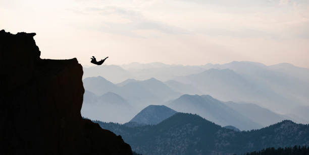 adventure of a man jumping with wingsuit towards spectacular landscapes stock photo
