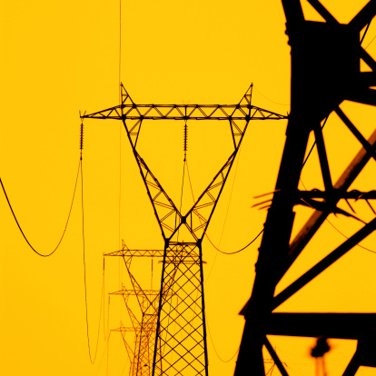 close up power lines and towers during sunset.
