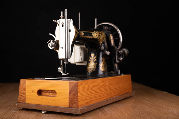 istock Old sewing machine on a dark table. An antique device for small housework. Dark background. 1183436260