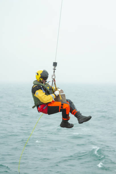 coast guard search and rescue helicopter sar training, hoisting a person at sea - rescue helicopter water searching imagens e fotografias de stock