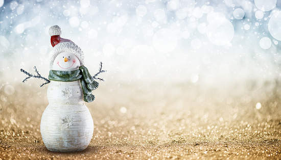 Cute snowman in a woolen sweater, hat and scarf against the background of a Christmas tree.