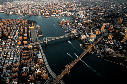 Brooklyn Bridge, Manhattan Bridge, and Williamsburg Bridge over the East River connecting Manhattan Island to Brooklyn, NYC, taken from a helicopter at golden hour.