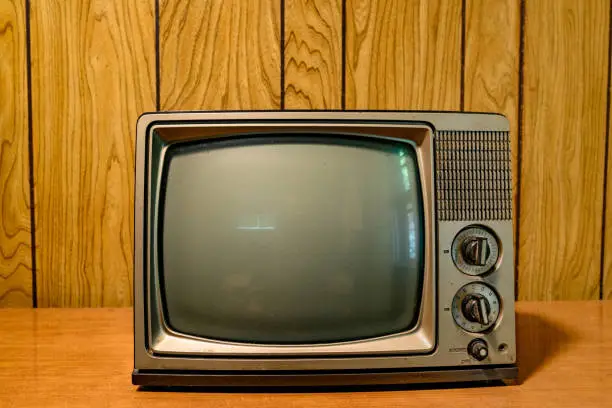 Photo of Small Retro Televison with Vintage Knobs in Front of a Wood Paneled Wall