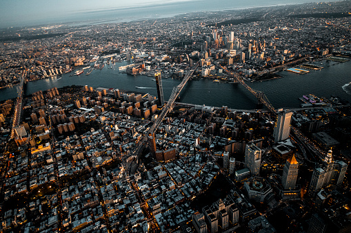 Brooklyn Bridge, Manhattan Bridge, and Williamsburg Bridge captured from air over the Lower Manhattan at dusk.