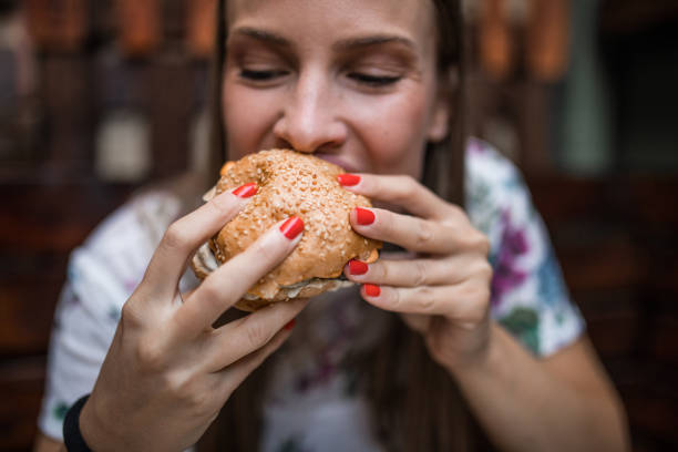 kobieta jedzenie burger - finger licking zdjęcia i obrazy z banku zdjęć