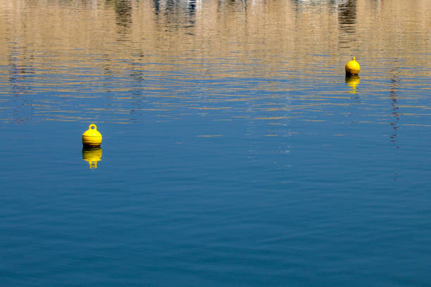 boya amarilla brillante sobre una tranquila superficie de agua azul. concepto de seguridad y protección. - sea water single object sailboat fotografías e imágenes de stock