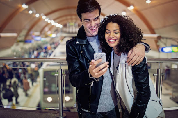 istock Happy couple is texting on the subway platform 1183448585