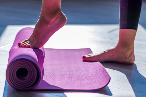donna srotolando tappetino da yoga con le sue punta di piedi - unrolling foto e immagini stock