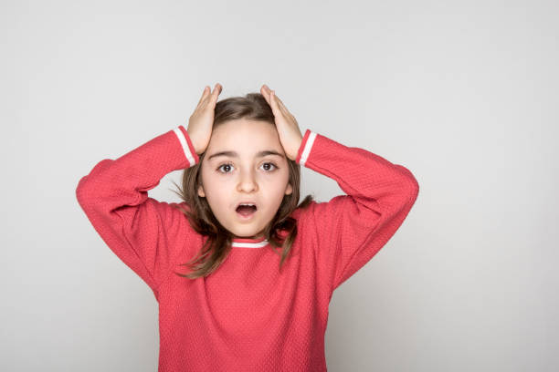 istock Excited girl holding hands on head, looking at camera 1183453236