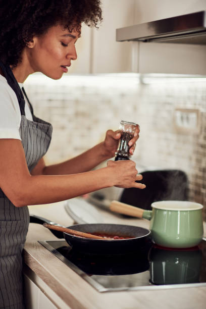 istock Woman putting pepper in tomato sauce. 1183454228
