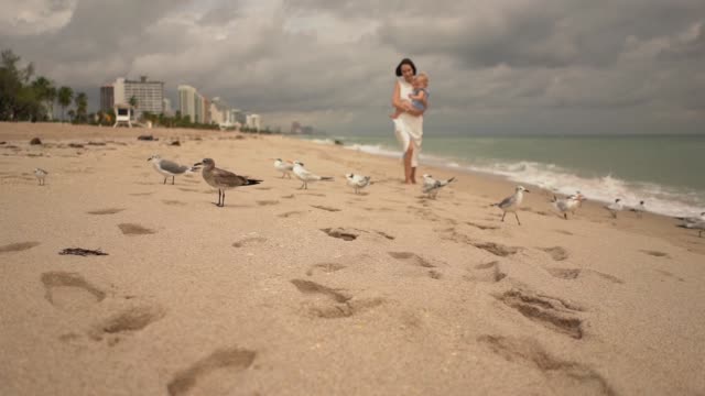 Slow motion video of mother and baby walking on the beach