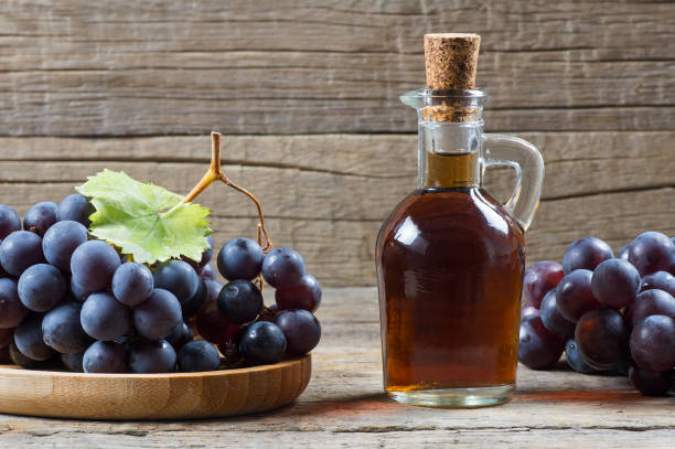 bottiglia di vetro di aceto balsamico di uva nera biologica a base di uve fresche fermentate. cibo biologico sano frutta nera, messa a fuoco selettiva - food balsamic vinegar vinegar bottle foto e immagini stock