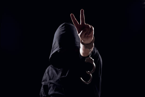 istock man hand showing the victory sign with handcuffs. 1183470619