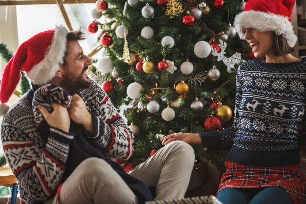 istock Cheerful couple opening presents under the Christmas tree 1183472189