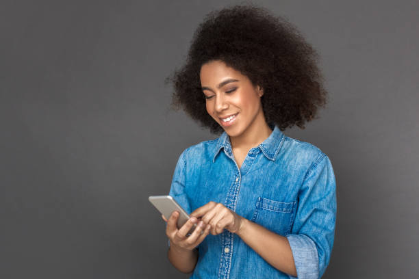 istock Freestyle. woman standing isolated on grey browsing smartphone joyful 1183472344