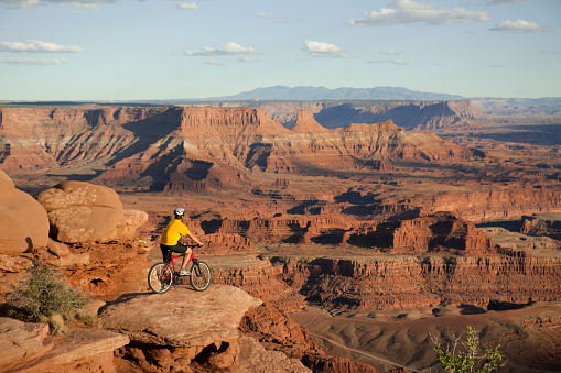 Man sitting on bicycle looking at magnificent view in Canyonlands National Park, Moab, Utah.