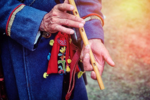 istock Nomad in traditional clothes playing the flute. Hands of an old man with a national pipe. A musician from a nomadic tribe plays the national flute. 1183473012