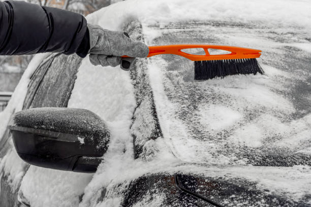 mann mit pinsel, um schnee aus dem auto zu entfernen - eiskratzer stock-fotos und bilder