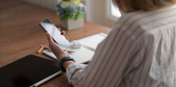 istock Close-up view of young female designer holding smartphone while working on her project 1183502305