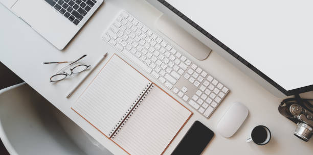 istock Cropped shot of modern workplace with open blank notebook, keyboard computer and desktop computer 1183502308