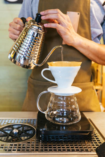 istock Barista making pour-over coffee with alternative method called Dripping. Coffee grinder, coffee stand and pour-over on a wooden table. 1183503561