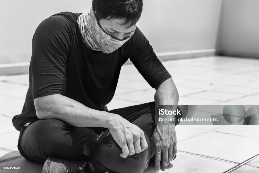 Asian man sitting on the street, discouraged and tired. Protester sitting on the sidewalk with his head down, exhausted and sad. Protest Stock Photo