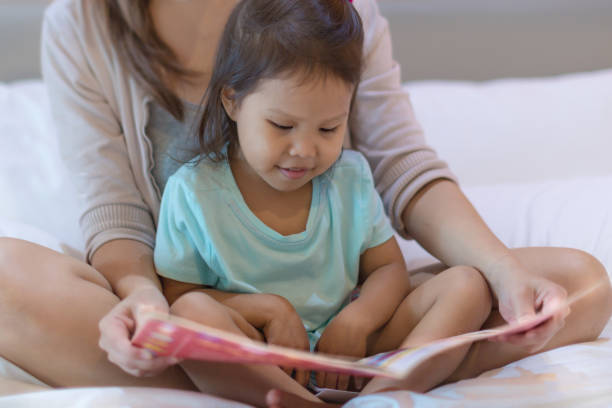 istock A child enjoying reading a book in bed with her mother. 1183504135