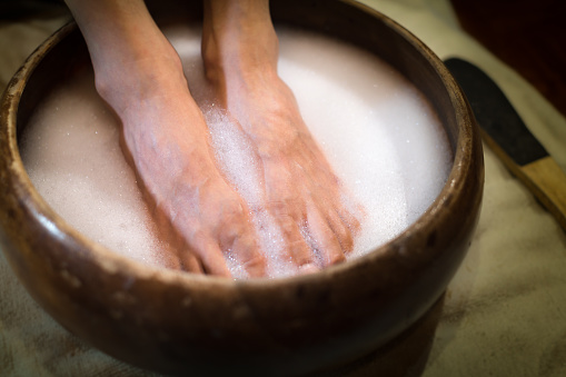 Feet soaking in suds water at a beauty nail spa.