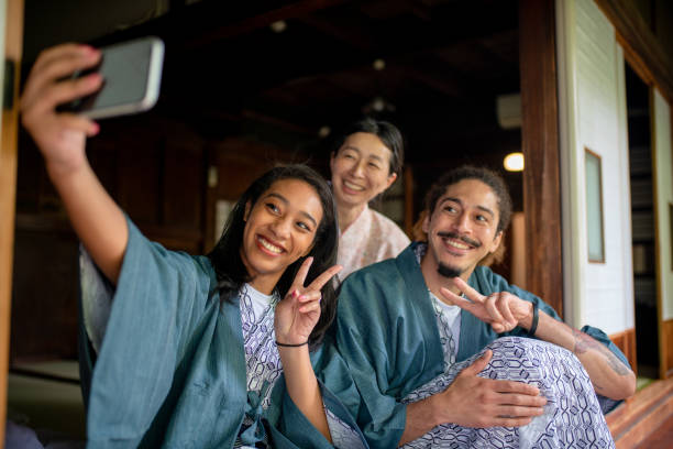 Guests at a traditional Japanese Ryokan (hotel) taking a selfie with the owner Guests at a traditional Japanese Ryokan (hotel) taking a selfie with the owner. Tokyo, Japan yukata photos stock pictures, royalty-free photos & images