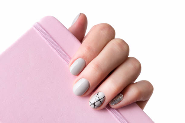 istock Females hand with modern manicure holds pink notepad close up 1183511329