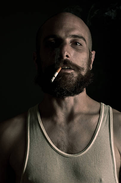 Man holding a matchstick on fire and blowing it. Black and white photograph.