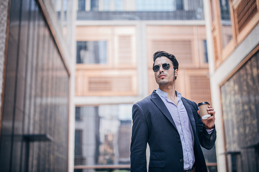 Handsome businessman with a coffee cup standing outdoors