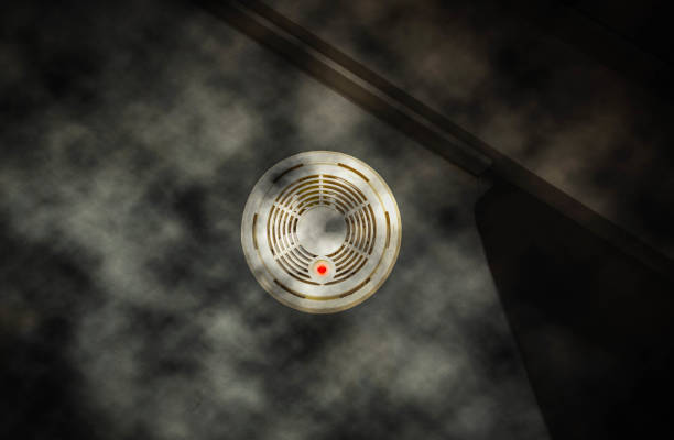 Smoke detector on the wall with red warning light sensor and smoke. fire concept, House on fire Dark