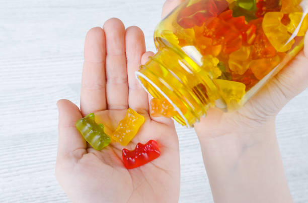 ребенок держит витамины для детей, как желе конфеты - capsule vitamin pill red orange стоковые фото и изображения