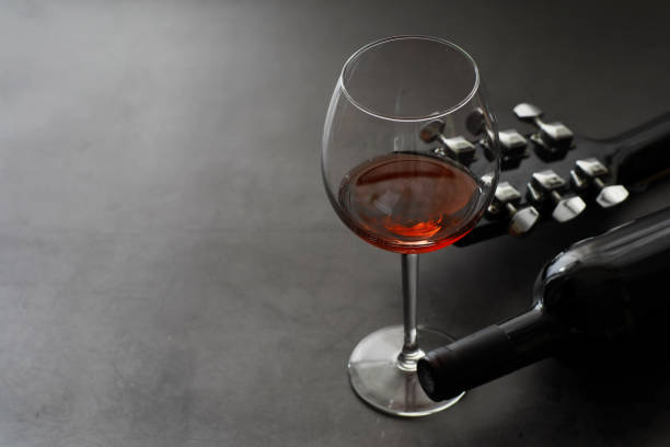 istock Guitar and high glass with red wine on a stone background. 1183537315