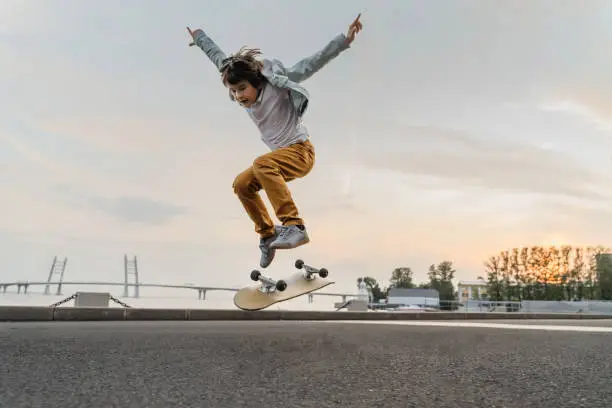 Photo of Boy jumping on skateboard at the street.