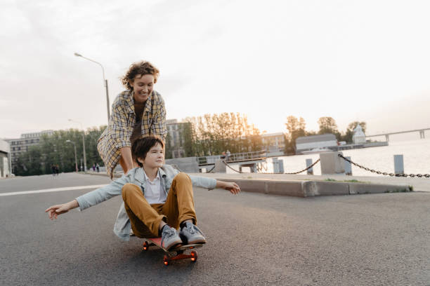 istock Happy mother riding her son on a skateboard. 1183539651