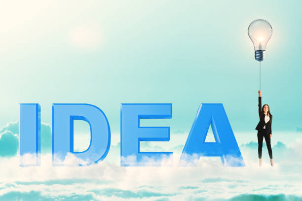 Attractive young european businesswoman with creative lamp balloon standing next to blue idea text on bright sky background. Freedom and inspire concept