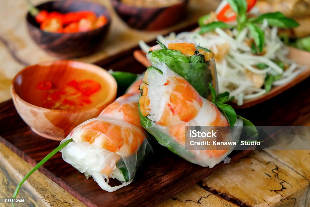 Vietnamese prawn summer rolls close up shot of sliced Vietnamese prawn spring rolls with spicy dipping sauce and green papaya salad Goi Cuon Stock Photo