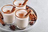 Homemade vanilla Christmas drink Eggnog in glass with grated nutmeg and cinnamon sticks
