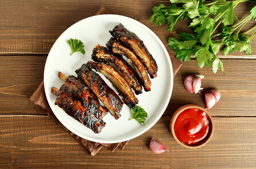 Grilled pork ribs on white plate. Tasty bbq meat. Top view, flat lay
